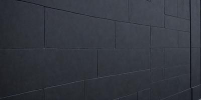The primary subject of the image is a black brick wall. The setting is a dark room, and the visual style is a photo. The dominant colors are black and grey, creating a moody atmosphere.