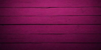 The primary subject of the image is a wooden wall with a purple color. The setting is a room with a wooden floor. The visual style is a close-up of the wooden wall, showcasing its texture and color. The dominant colors are purple and brown, creating a warm and inviting atmosphere.