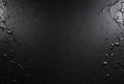 The primary subject of the image is a black surface, which appears to be a leather or suede material. The setting is a dark room, and the visual style is a close-up of the black surface. The colors and mood of the image are predominantly dark and moody, with the black surface being the main focus.