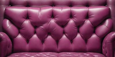 The primary subject of the image is a purple couch with a leather-like texture. The couch is the main object in the scene, and it is set against a purple background. The visual style of the image is a close-up of the couch, showcasing its texture and color. The dominant colors in the image are purple and pink, creating a warm and inviting atmosphere.