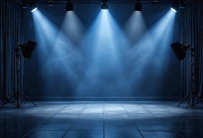The primary subject of the image is a large, empty room with a blue background. The room appears to be a stage or a studio, as it is illuminated by bright lights. The visual style of the image is a photo, capturing the lighting and the overall atmosphere of the room. The colors and mood of the image are predominantly blue, creating a calm and serene environment.