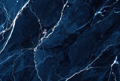 The primary subject of the image is a close-up of a marble surface with a blue tint. The setting is a dark room, and the visual style is a photo. The dominant colors are blue and black, creating a moody atmosphere.