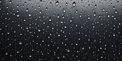 The primary subject of the image is a rainy day, as evidenced by the raindrops falling on a black background. The setting is a dark, rainy environment, and the visual style is a close-up of the raindrops. The colors and mood of the image are predominantly dark and moody, with the raindrops creating a sense of wetness and gloominess.