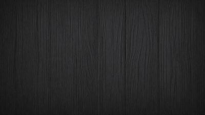 The primary subject of the image is a wooden wall. The setting is a dark room, and the visual style is a close-up of the wooden wall. The colors and mood of the image are predominantly dark, with the wooden wall being the main focus.