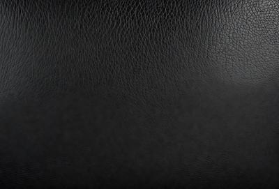 The primary subject of the image is a black leather seat. The setting is a black background, which creates a contrast with the leather seat. The visual style is a close-up of the leather seat, showcasing its texture and details. The colors and mood of the image are dark and moody, emphasizing the leather seat as the focal point.