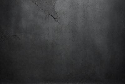The primary subject of the image is a large, gray, concrete wall. The setting is an outdoor environment, with the wall being the main focus of the scene. The visual style of the image is a photo, capturing the concrete wall in its natural state. The colors and mood of the image are predominantly gray and dull, giving it a somewhat drab and uninviting appearance.