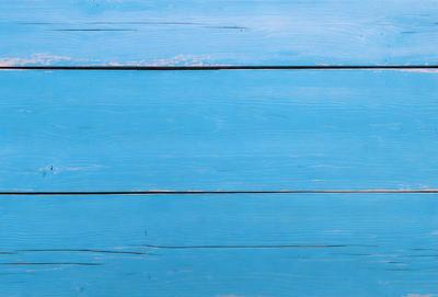The primary subject of the image is a blue wooden wall. The setting is a room with a blue wooden wall, and the visual style is a photo. The dominant colors are blue and white, creating a calm and serene atmosphere.