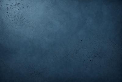 The primary subject of the image is a blue background with a few black specks. The setting is a dark room, and the visual style is a close-up of the blue background. The colors and mood of the image are predominantly dark and moody, with the blue background providing a contrasting element.