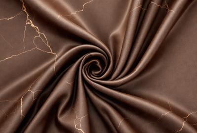 The primary subject of the image is a brown fabric, possibly a piece of cloth or a curtain. The setting is a close-up view of the fabric, showcasing its texture and details. The visual style is a realistic representation of the fabric, with no indication of digital art or illustration. The colors and mood of the image are predominantly brown, giving it a warm and earthy atmosphere.