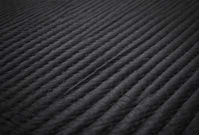 The primary subject of the image is a black fabric with a pattern of white stripes. The setting is a black background, and the visual style appears to be a photo. The dominant colors are black and white, creating a contrasting and visually striking scene.