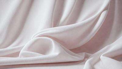 The primary subject of the image is a white sheet of fabric. The sheet is folded and draped over a pink surface, creating a visually appealing contrast between the white and pink colors. The visual style of the image is a close-up of the fabric, showcasing its texture and details. The overall atmosphere of the image is elegant and sophisticated, with the white sheet and pink background creating a harmonious and pleasing aesthetic.