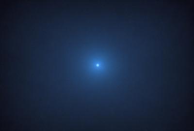 The primary subject of the image is a bright blue star, which is the main focus of the scene. The setting is a dark, cloudy sky, creating a dramatic backdrop for the star. The visual style of the image is a photo, capturing the beauty of the celestial object. The colors in the image are predominantly dark and blue, with the bright blue star standing out against the dark sky. The overall atmosphere of the image is serene and captivating.