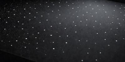 The primary subject of the image is a black leather surface with a pattern of white dots. The setting is a black background, and the visual style appears to be a photo. The dominant colors are black and white, creating a contrasting and visually striking scene.