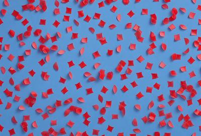 The primary subject of the image is a large number of red and pink hearts scattered across a blue background. The hearts are of various sizes and shapes, creating a visually appealing pattern. The setting appears to be a blue wall or surface, which serves as the backdrop for the hearts. The visual style of the image is a combination of digital art and illustration, as the hearts are carefully arranged and the overall composition is well-executed. The dominant colors in the image are red and pink, which evoke a sense of