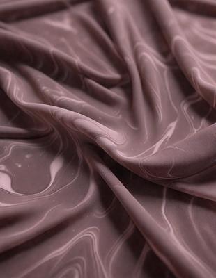The primary subject of the image is a piece of fabric, which appears to be a brown or purple material. The setting is a room with a table, and the visual style is a close-up of the fabric. The colors and mood of the image are predominantly brown and purple, giving it a warm and cozy atmosphere.
