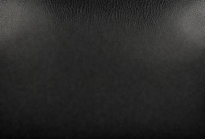 The primary subject of the image is a black leather seat. The setting is a black background, which creates a contrast with the leather seat. The visual style is a close-up of the leather seat, showcasing its texture and details. The colors and mood of the image are dark and moody, emphasizing the leather seat's richness and luxury.