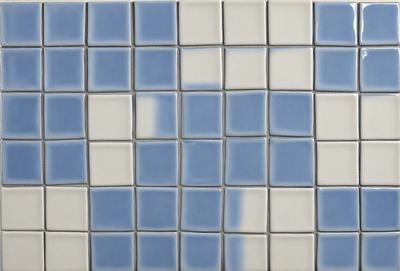 The primary subject of the image is a blue and white tile wall. The setting is a room with a blue and white checkered tile pattern. The visual style is a close-up of the tile wall, showcasing the intricate design. The dominant colors are blue and white, creating a calm and soothing atmosphere.