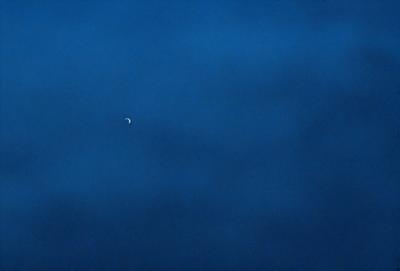 The primary subject of the image is a small, bright planet, which is the main focus of the scene. The setting is a vast, dark blue sky, with no clouds or other objects visible. The visual style is a photo, capturing the beauty of the planet against the backdrop of the night sky. The colors and mood of the image are dominated by the dark blue of the sky and the brightness of the planet, creating a sense of awe and wonder.