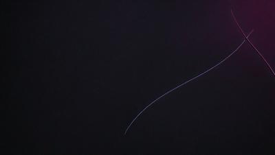 The primary subject of the image is a long, thin line or streak of light, which appears to be a lightning bolt or a laser beam. The setting is a dark, starry night sky, with no visible landmarks or objects. The visual style is a black and white photo, which adds a dramatic and artistic touch to the scene. The colors and mood of the image are predominantly dark and moody, with the light streak standing out against the black sky.