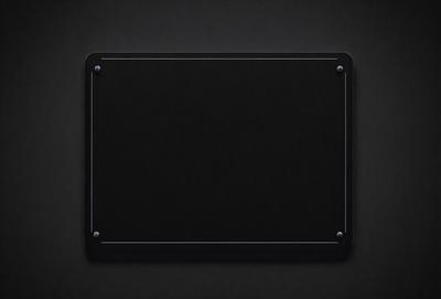 The primary subject of the image is a black square with a hole in the middle. The square is placed on a black background, giving it a contrasting appearance. The visual style of the image is a close-up of the square, emphasizing its shape and texture. The colors and mood of the image are predominantly dark, with the black square and background creating a sense of depth and mystery.