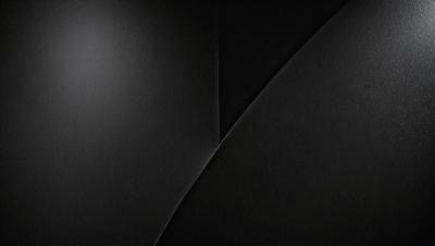 The primary subject of the image is a black and white photograph of a wall. The setting is a dark room, and the visual style is a close-up of the wall. The colors and mood of the image are predominantly black and white, creating a moody and dramatic atmosphere.
