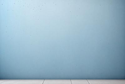 The primary subject of the image is a blue wall with a few white specks on it. The setting is a room with a wooden floor. The visual style is a photo, and the colors and mood are predominantly blue and calm.