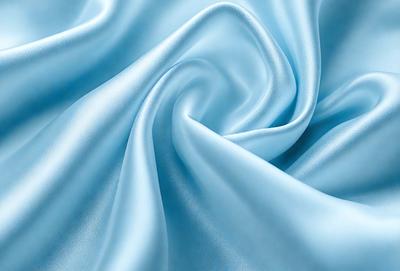 The primary subject of the image is a blue fabric, which appears to be a piece of silk. The setting is a room with a blue background, and the visual style is a close-up of the fabric. The colors and mood of the image are predominantly blue, creating a calm and serene atmosphere.