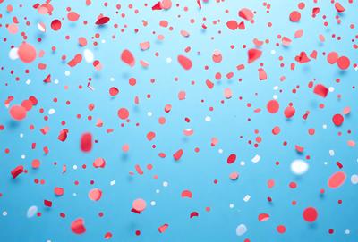 The primary subject of the image is a blue background with red and white confetti floating in the air. The confetti is scattered throughout the scene, creating a visually appealing and festive atmosphere. The setting appears to be a celebration or event, as the confetti is a common decoration for such occasions. The visual style of the image is a combination of photo and digital art, as the confetti appears to be floating in a 3D space. The colors and mood of the image are predominantly blue, red