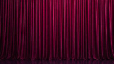 The primary subject of the image is a red curtain, which is the main object, scene, or focus of the image. The setting is a stage or theater, with the curtain hanging down in front of a purple background. The visual style is a photo, and the dominant colors are red and purple, creating a dramatic and intense atmosphere.