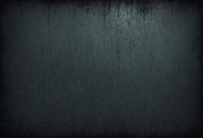 The primary subject of the image is a large, dark grey wall with a textured surface. The setting is a room with a black background, which creates a moody atmosphere. The visual style is a close-up of the wall, showcasing its texture and details. The colors and mood of the image are predominantly dark and dramatic, with the grey wall serving as the focal point.