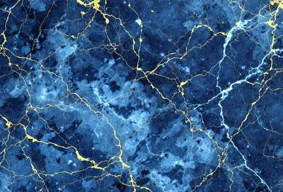 The primary subject of the image is a blue marble wall with a gold pattern. The setting is a room with a blue and gold marble wall, which serves as the background. The visual style is a close-up of the marble wall, showcasing its intricate design. The dominant colors are blue and gold, creating a luxurious and elegant atmosphere.