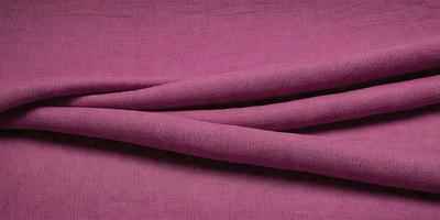 The primary subject of the image is a piece of pink fabric. The setting is a table, and the visual style is a close-up of the fabric. The colors and mood of the image are predominantly pink, creating a warm and inviting atmosphere.