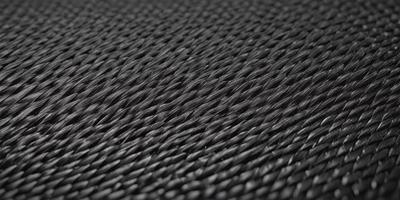 The primary subject of the image is a close-up of a black, textured fabric. The setting is a black background, which creates a striking contrast with the fabric. The visual style is a close-up of the fabric, showcasing its texture and pattern. The colors in the image are predominantly black, giving the image a bold and striking appearance.