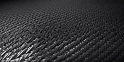 The primary subject of the image is a black mesh or weave, which is the main object, scene, or focus of the image. The setting or background consists of a black surface, possibly a wall or a piece of fabric. The visual style of the image is a close-up of the black mesh, which gives it a textured and detailed appearance. The colors and mood of the image are predominantly black, creating a sense of depth and contrast.