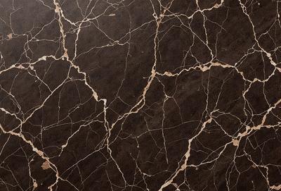 The primary subject of the image is a marble countertop with a brown and black color scheme. The setting is a kitchen, and the visual style is a close-up of the marble countertop. The countertop has a patterned texture, giving it a unique and elegant appearance. The colors and mood of the image are warm and sophisticated, creating a welcoming and stylish atmosphere.