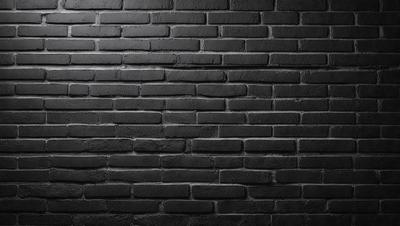 The primary subject of the image is a brick wall. The setting is a dark room, and the visual style is a black and white photo. The dominant colors are black and white, creating a moody atmosphere.