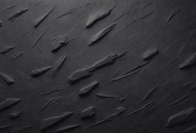 The primary subject of the image is a black surface with a pattern of thin, curved lines. The setting is a black background, and the visual style appears to be a combination of a photo and a drawing. The colors are predominantly black, and the overall atmosphere is somewhat mysterious and intriguing.