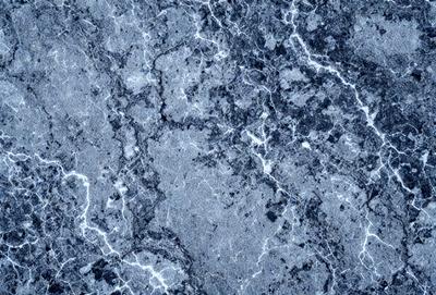 The primary subject of the image is a close-up of a marble surface, showcasing its intricate patterns and textures. The setting is a blue marble wall, which adds a striking contrast to the patterns. The visual style is a close-up of the marble, emphasizing its details. The colors and mood of the image are predominantly blue, creating a calm and serene atmosphere.