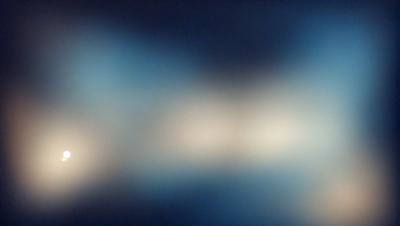 The primary subject of the image is a blue background with a pattern of white dots. The setting appears to be a dark room, and the visual style is a close-up of the blue background with the white dots. The colors and mood of the image are predominantly dark and moody, with the blue background and white dots creating a visually striking contrast.