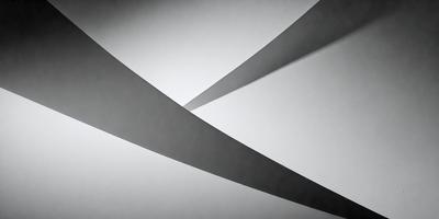 The primary subject of the image is a pair of black and white triangles. The setting is a white wall, and the visual style appears to be a digital art or illustration. The dominant colors are black and white, creating a bold and striking contrast. The overall atmosphere of the image is modern and minimalist.