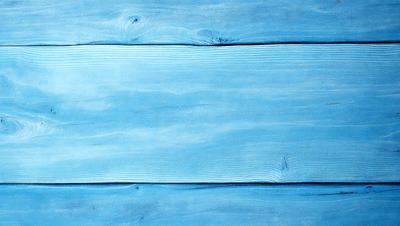 The primary subject of the image is a wooden plank with a blue background. The setting is a wooden wall, and the visual style is a close-up of the wooden plank. The colors and mood of the image are predominantly blue, creating a calm and serene atmosphere.