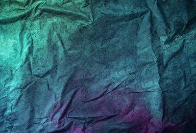 The primary subject of the image is a piece of paper with a purple and blue color scheme. The paper appears to be wrinkled and has a slightly textured appearance. The setting is a close-up of the paper, showcasing its unique texture and color. The visual style is a realistic representation of the paper, capturing its natural appearance. The colors and mood of the image are predominantly purple and blue, creating a calm and serene atmosphere.