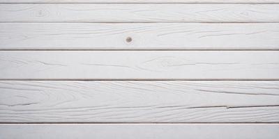 The primary subject of the image is a wooden deck with a white surface. The setting is an outdoor environment, and the visual style is a photo. The colors and mood of the image are predominantly white, giving it a clean and minimalist appearance.