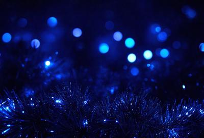 The primary subject of the image is a group of blue lights, which are scattered throughout the scene. The setting appears to be a dark environment, possibly a nighttime cityscape or a dark room. The visual style of the image is a combination of a photo and digital art, as the blue lights are depicted in a way that resembles a painting or a digital illustration. The colors and mood of the image are predominantly blue, creating a serene and calming atmosphere.