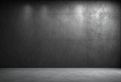 The primary subject of the image is a large, empty room with a grey cement wall. The setting is a concrete room, and the visual style is a black and white photo. The room appears to be a large, empty space with a grey cement wall, giving it a somewhat dull and uninviting atmosphere.