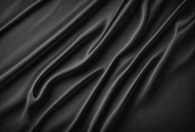 The primary subject of the image is a black fabric, which appears to be a piece of cloth or a curtain. The setting is a dark background, which contrasts with the black fabric. The visual style is a close-up of the fabric, showcasing its texture and details. The colors and mood of the image are predominantly dark, with the black fabric being the main focus.