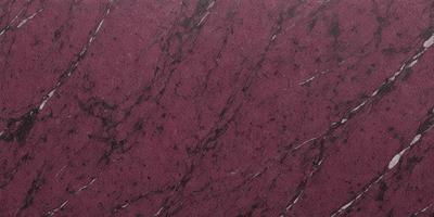 The primary subject of the image is a marbled surface, which appears to be a marble wall or countertop. The setting is indoors, with the marbled surface being the main focus of the image. The visual style is a close-up of the marbled surface, showcasing its intricate patterns and textures. The colors and mood of the image are predominantly red, giving it a warm and luxurious appearance.