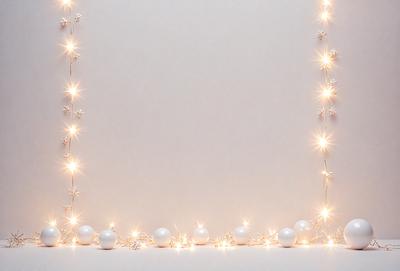 The primary subject of the image is a white wall with a string of lights attached to it. The lights are shining brightly, creating a warm and inviting atmosphere. The setting is a simple white wall, and the visual style appears to be a photo. The colors and mood of the image are predominantly white, with the lights adding a touch of warmth and brightness to the scene.
