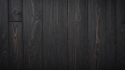 The primary subject of the image is a wooden floor. The setting is a room with a wooden floor, and the visual style is a photo. The colors and mood of the image are predominantly dark, with a focus on the wooden floor.