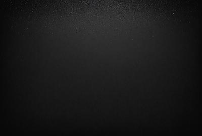 The primary subject of the image is a black background with a few white specks. The setting is a dark room, and the visual style is a black and white photo. The colors and mood of the image are predominantly dark and moody, with the white specks adding a touch of contrast.